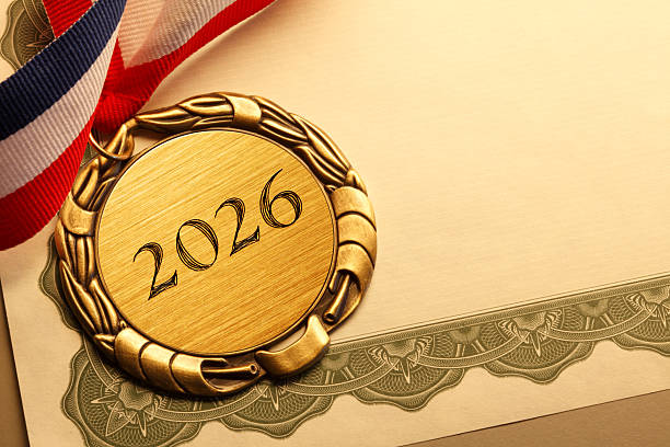 A gold medal engraved with 2026 is attached to a red white and blue ribbon as it rests on top of a blank award certificate.