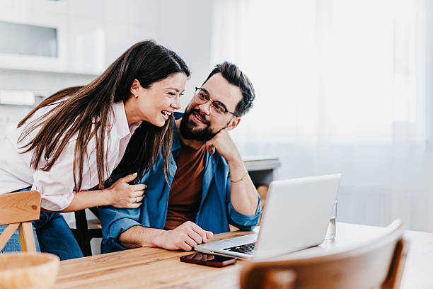 istock Happy couple laughing and using laptop at home 2226009200