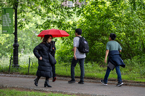 New York, New York, USA May 23, 2025 Pedestrians walking in the rain in Central Park.