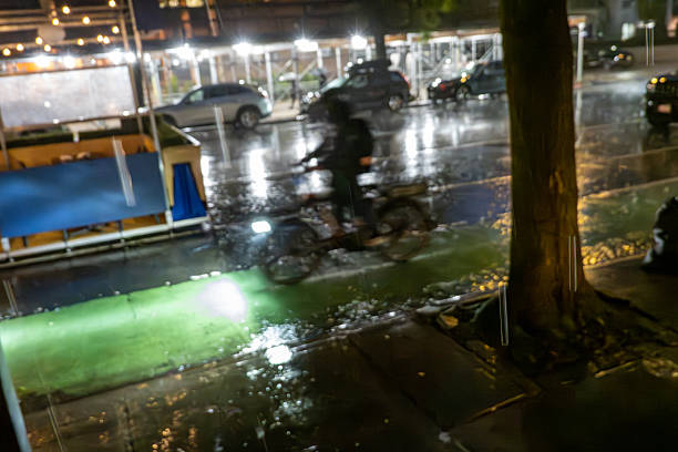 A Meituan delivery driver checks his phone while standing next to his motorbike in front of a Nike store on September 1, 2024 in Chongqing, China. The Chongqing Meteorological Observatory continued to issue a red high-temperature warning, marking the 12th consecutive day of such an alert.