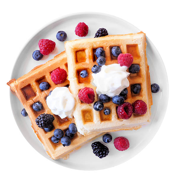 istock Breakfast waffles with fresh berries and whipped cream on a white plate isolated on white 2226010732