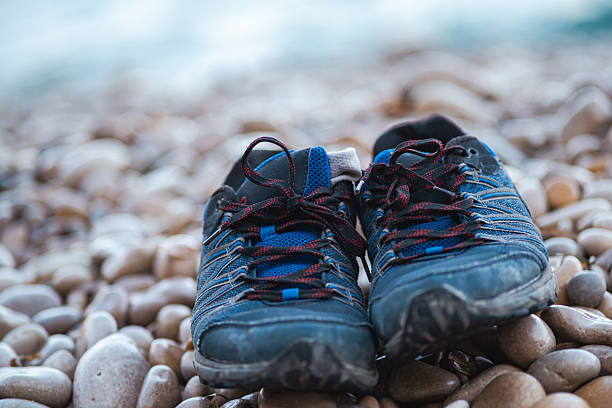 A serene view of a pair of Schuhe left on the sandy beach, capturing the essence of relaxation and simplicity by the sea. The image reflects a quiet moment of pause, where the shoes are set aside to enjoy the feel of the sand and the gentle waves. This scene evokes a sense of freedom and connection with nature, making it a tranquil and reflective beachside experience.