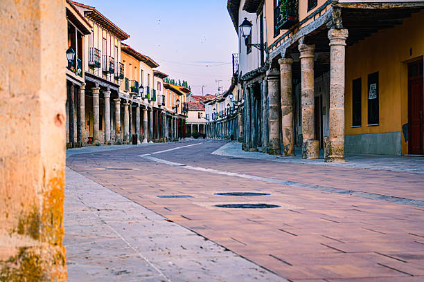 Traditional street in Ampudia, Palencia (Spain), with arcades, rustic wooden columns and historic houses illuminated by the warm light of sunset.