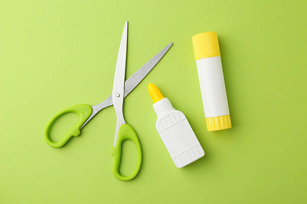 istock Different types of glue and scissors on green background, flat lay 2226033972