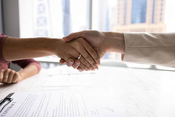 istock Two female business partners shaking hands over paper contract 2226035066