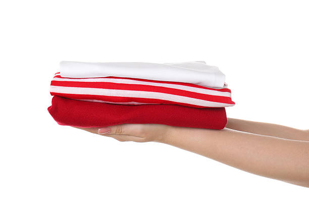 Woman holding stack of clothes on white background, closeup