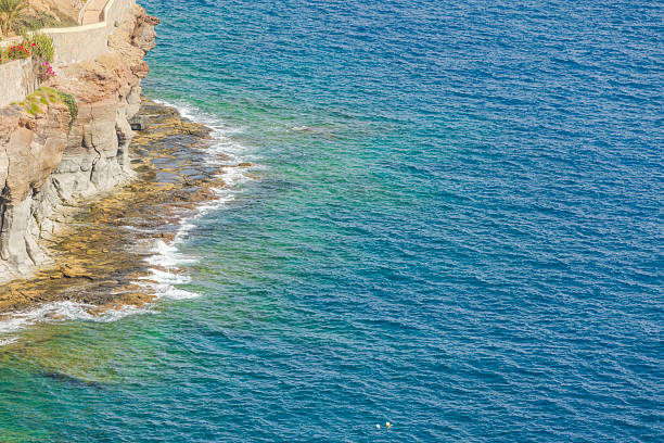 Rocky Atlantic Ocean coastline with turquoise waves crashing against stone cliffs in Gran Canaria. Spain.