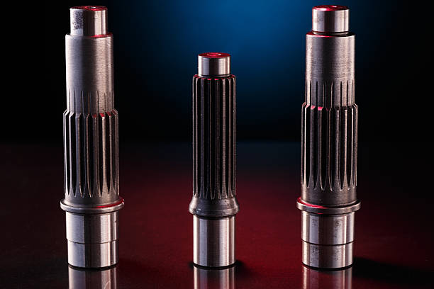 Three metallic shafts stand in a row on a dark surface