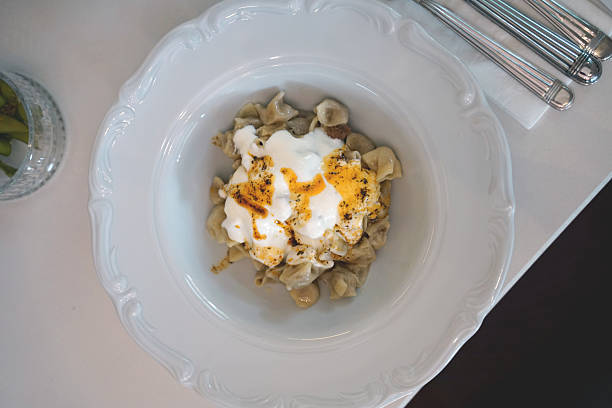 Top view of a plate of mantı — Turkish dumplings garnished with yogurt, paprika, and dried mint. A classic and beloved dish in Turkish culinary culture.