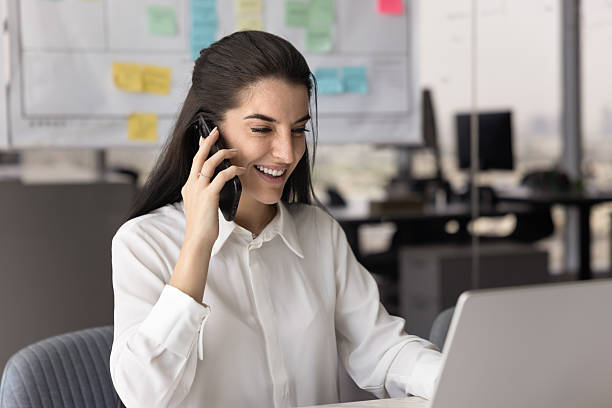 istock Businesswoman having positive conversation on smartphone while using laptop 2226046067
