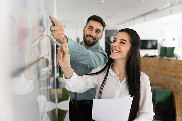 istock Two happy Latin workmates working together standing next to whiteboard 2226047718