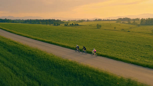 istock Three cyclists race on a country road, surrounded by lush green fields and a beautiful sky 2226052729