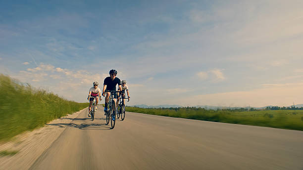 Male and female riders riding road bikes on mountain road.