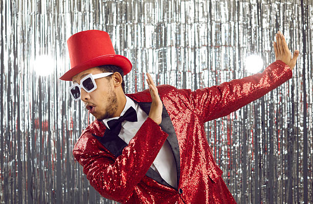 istock Dark-skinned guy in bright tuxedo with sequins shows dance show on shiny silver background. 2226083319