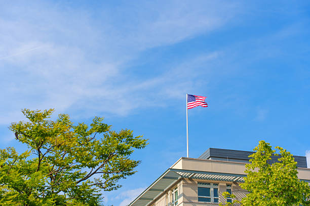 istock American Flag Flying Above Modern Building Surrounded By Green Trees Under Blue Sky 2226093150
