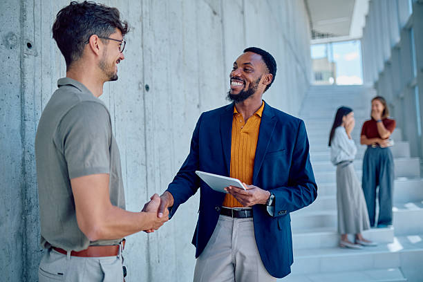 istock Two businessmen shaking hands while holding tablet in modern office building 2226096043