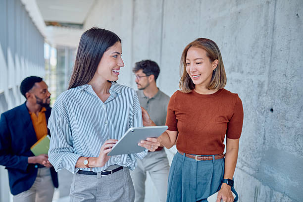 istock Businesswomen walking and talking in office corridor using tablet 2226096068