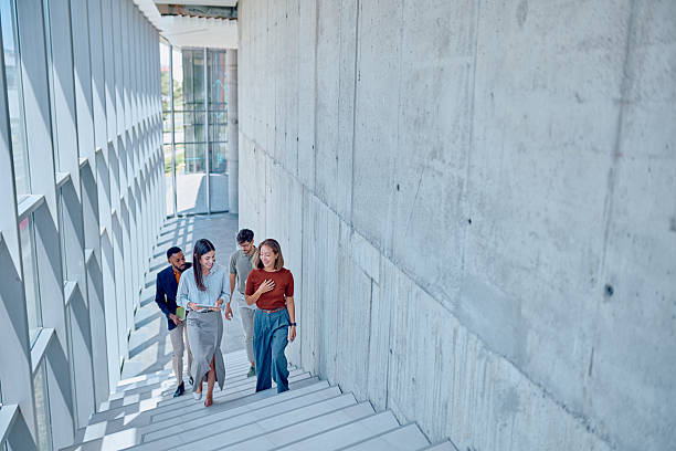 istock Businesspeople walking down stairs in modern office building 2226096072