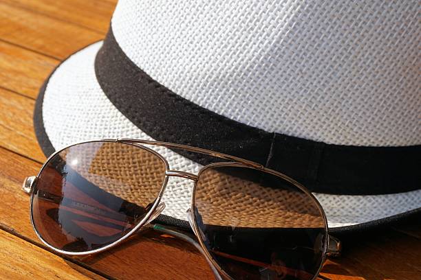 Men's fedora and sunglasses on wooden surface