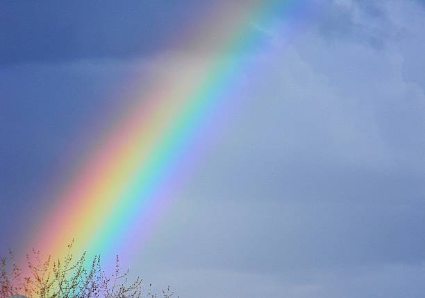 Rainbow in blue partly cloudy sky with sunlight at day