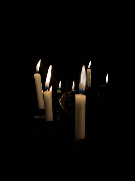 istock White Wax Candles Burning in Complete Darkness with Soft Yellow Flames on Black Background 2226097772
