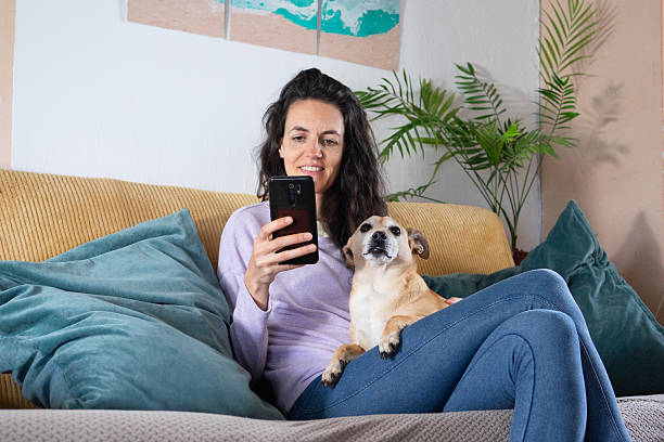 istock Woman relaxing on sofa with dog and using smartphone 2226101783