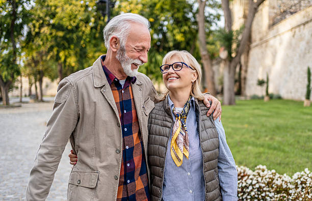 istock Happy senior couple walking and smiling in a park 2226104321