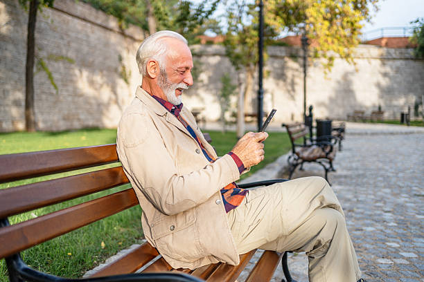 istock Senior man using smartphone sitting on bench in park 2226104443