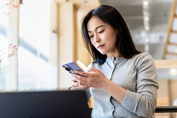 istock An Asian woman using mobile phone and computer in a coffee shop 2226108997
