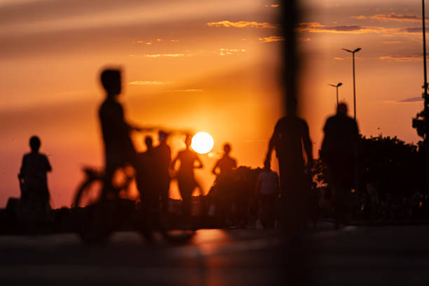 Walking people silhouettes on the street with reflections at sunset.