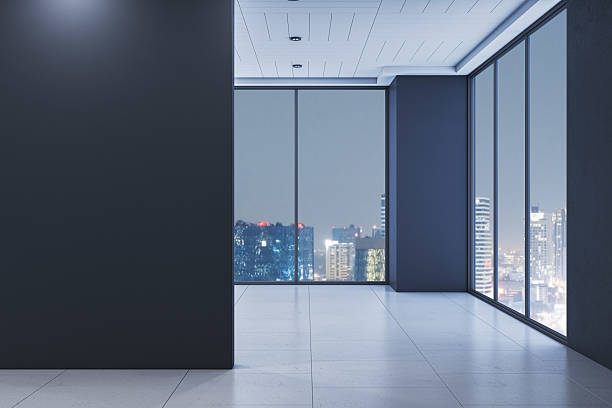 istock Modern empty office room interior with large glass windows overlooking illuminated city skyline at night, clean tiled floor and dark walls. 3D Rendering 2226112662
