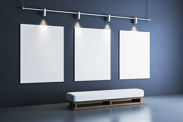 Three vertical blank posters on a dark gallery wall with spotlights above and a white bench below, showcasing a clean modern exhibition interior. 3D Rendering.