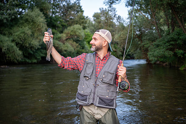 istock Man smiling while fly fishing in a scenic river landscape 2226121197