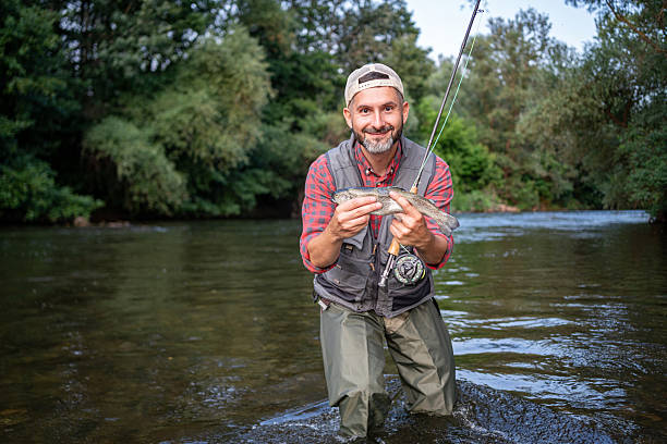 istock Man Fly Fishing in a River Surrounded by Lush Greenery 2226121505
