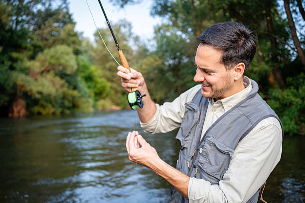 istock Man fly fishing on a tranquil river surrounded by lush greenery 2226121955