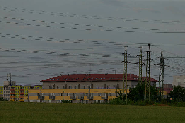 A large and prominent building featuring a striking red roof is surrounded by numerous overhead power lines in the vicinity