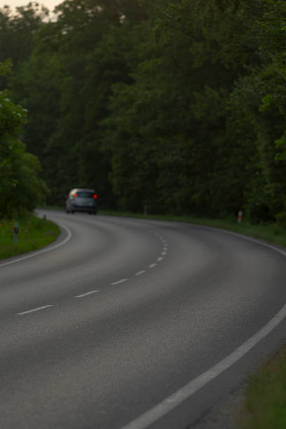 istock A car is smoothly driving down a curvy road winding through the woods 2226122498