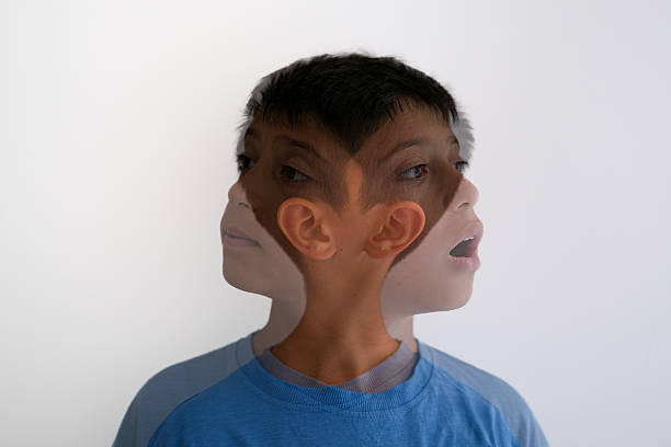 Creative double exposure image of a young boy wearing a blue shirt, captured with his head turned in opposite directions. The overlapping profiles create a surreal and expressive visual effect, symbolizing concepts like confusion, decision-making, inner conflict, or psychological complexity. Isolated on a plain white background for versatile use in artistic, conceptual, or editorial projects.
