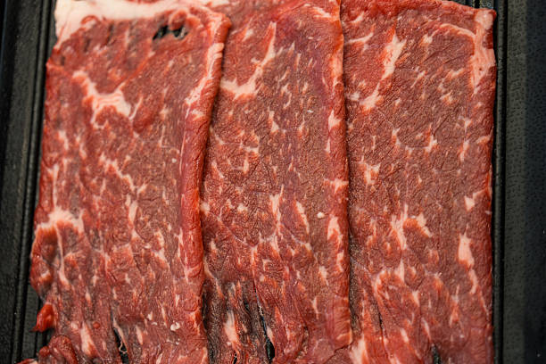 Raw freshly prepared thin beef for hot pot and Japanese sukiyaki on black tray
