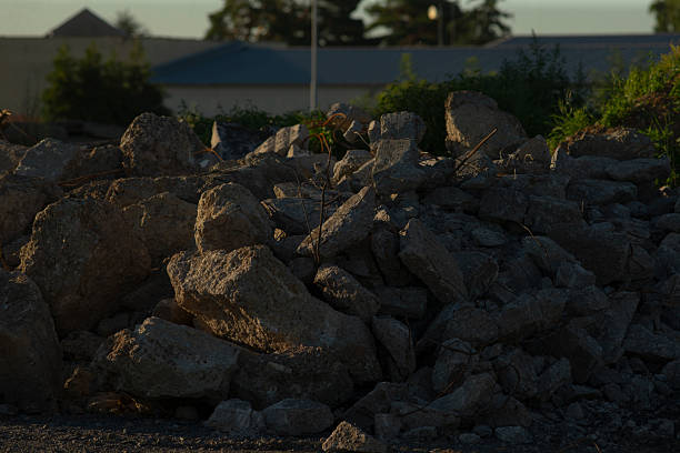In front of a house, there is a sizable pile of rocks that is resting on the ground, creating an interesting visual feature in the landscape