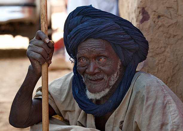 Mhaireth, Mauritania. October 05, 2021 Portrait of a very elderly Moorish man with a blue turban on his head sitting in the shade of a village hut near the oasis.