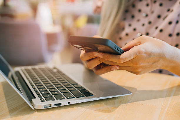 istock Close-Up of Person Using Smartphone Next to Laptop 2226130319