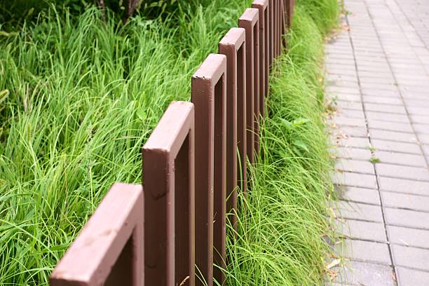 A brown fence with green grass in between. The fence is made of wood and is brown in color