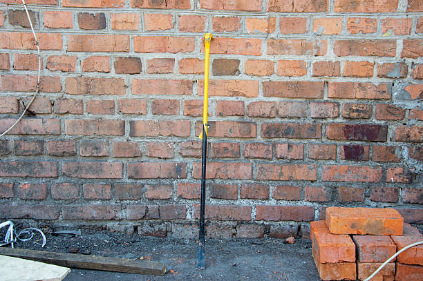istock A yellow-handled tool stands upright near a brick wall, surrounded by construction materials and a dust-covered ground 2226138989