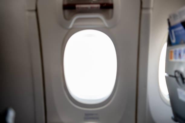 Looking through an airplane window while flying over clouds