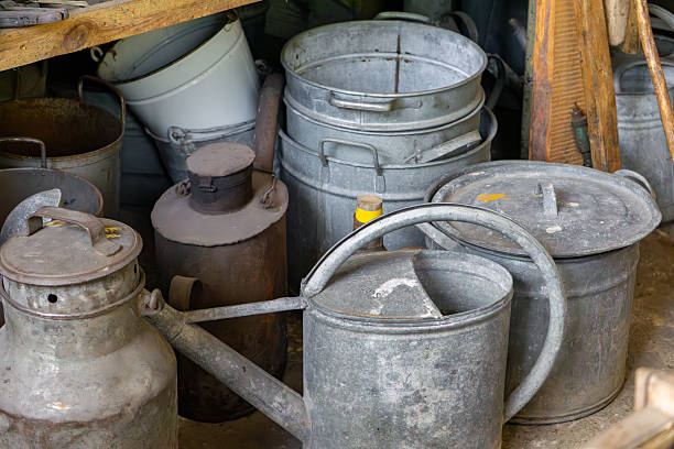 istock Old metal watering cans, buckets, and milk churns arranged in a rustic storage space. Visible signs of use and patina give the objects a vintage countryside look. 2226144218