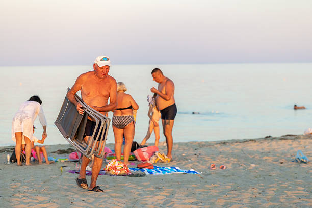 A family on a calm beach is gathering their chairs and belongings, getting ready to leave as their day by the sea concludes.