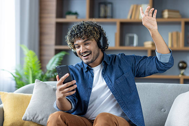istock A cheerful man waves while on a video call from his living room. 2226144841