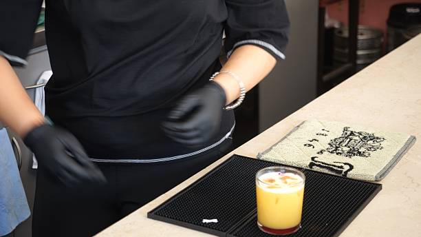Skilled Bartender Prepares a Refreshing Orange Cocktail with Ice and Garnishes in a Cozy Lombardy Bar Setting Creating an Inviting Ambiance for Patrons