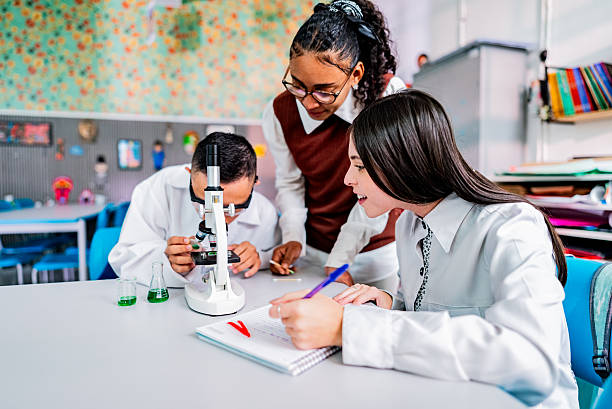 istock Teacher assisting students with chemical experiment of microscope used in laboratory 2226160452